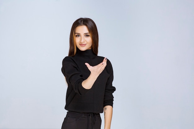 Girl in black shirt pointing someone ahead. High quality photo