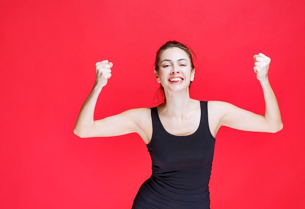 Girl in black shirt showing fists and feeling happy. High quality photo