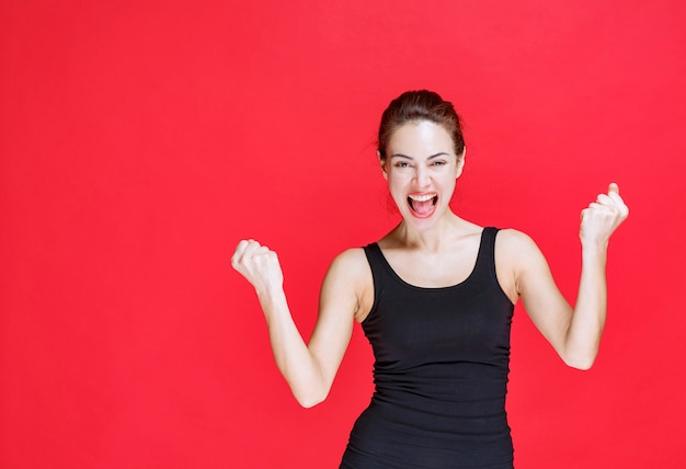 Girl in black shirt showing fists and feeling happy. High quality photo