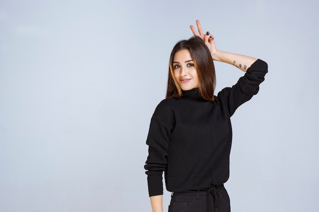 Girl in black shirt showing rabbit ear sign. High quality photo