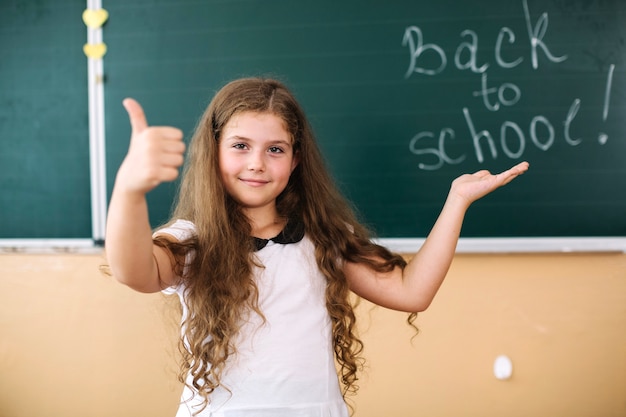 Girl at blackboard showing thumb up