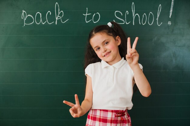 Girl at blackboard showing two fingers