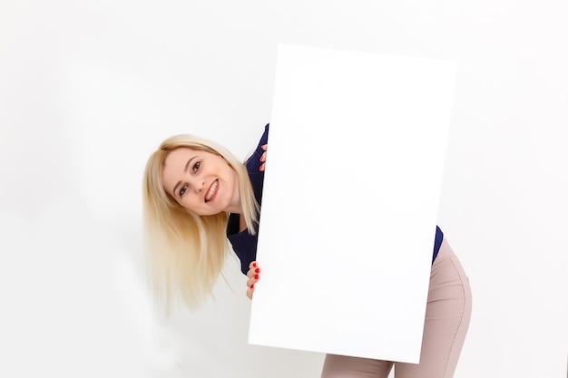 Girl and blank canvas. copy space on canvas board for image or message. young woman looking at mockup poster and standing over grey background.