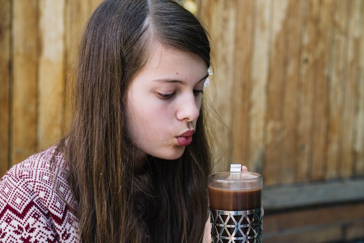 Free Photo girl blowing over the hot chocolate drink