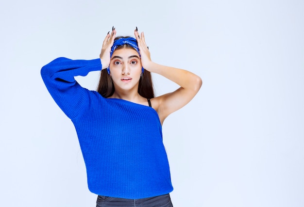 Girl in blue party dress holding head as she is confused and surprized.