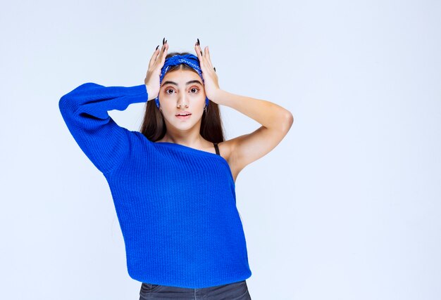 Girl in blue party dress holding head as she is confused and surprized.