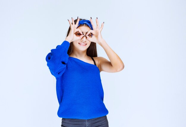 Girl in blue party shirt looking across her fingers.