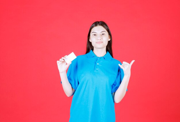 Девушка в синей рубашке, представляя свою визитную карточку и указывая на своего коллегу вокруг