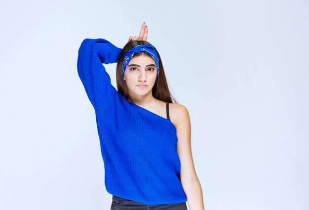 Girl in blue shirt showing rabbit ears.