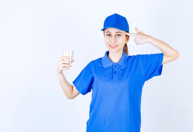 Girl in blue uniform holding a cup of drink and thinking or has new idea.