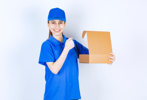 Girl in blue uniform holding an open cardboard takeaway box and showing her fist.
