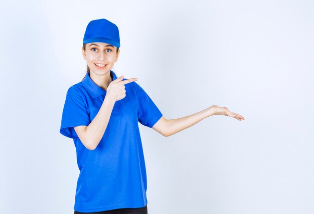 Girl in blue uniform pointing at something on the right.