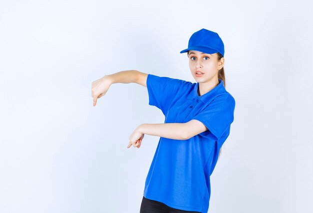 Girl in blue uniform showing something below.