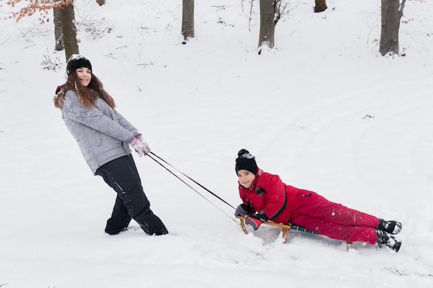 Девочка и мальчик весело кататься на санях по снежному пейзажу