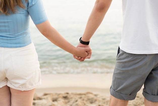 Girl and boy holding hands on the beach close-up