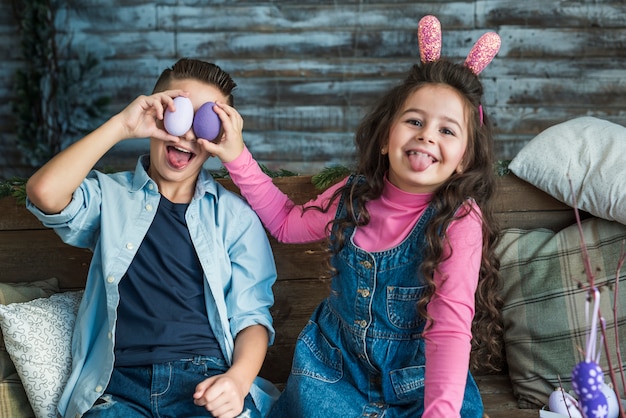 Girl and boy with Easter eggs making faces