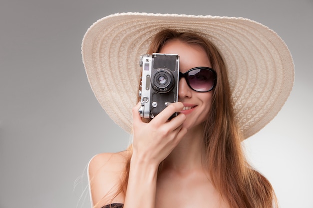 Girl in broad brimmed hat  and sunglasses with retro camera