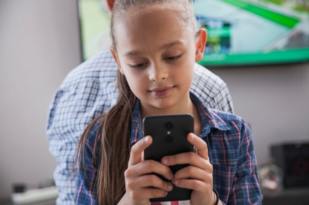 Girl browsing smartphone near teenager