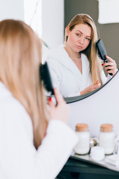 Girl brushing her hair at the bathroom