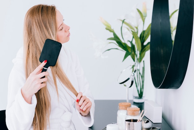 Girl brushing her hair at the bathroom