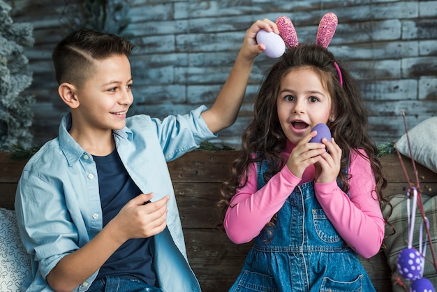 Foto gratuita ragazza nelle orecchie del coniglietto e ragazzo che gioca con le uova di pasqua