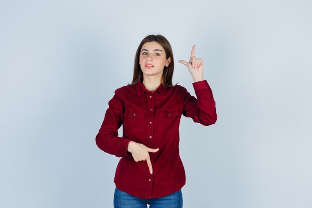 Girl in burgundy blouse pointing up and down and looking confident