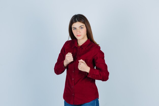 girl in burgundy shirt standing in fight pose and looking confident.