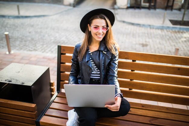 Girl business woman sit on wood bench in the city in the park in autumn