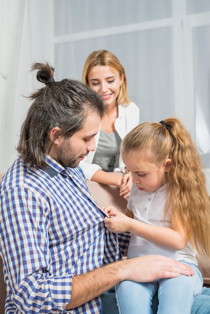 Girl buttoning her father's shirt