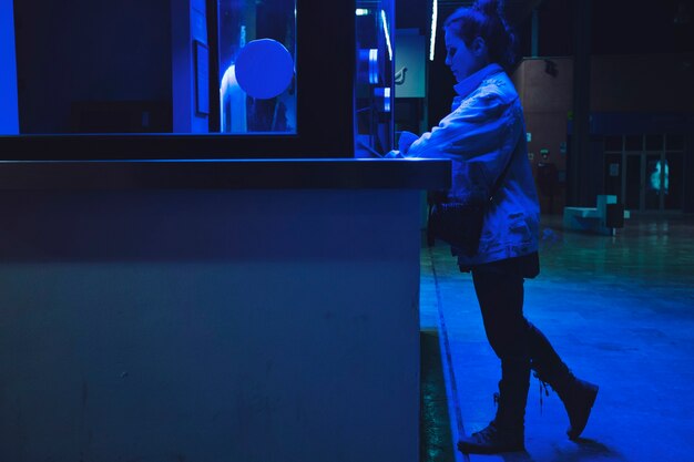 Girl buying tickers in neon light