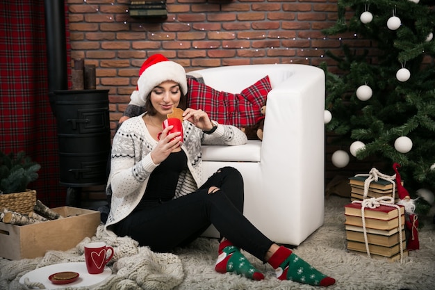 Foto gratuita ragazza dall'albero di natale in un cappello rosso