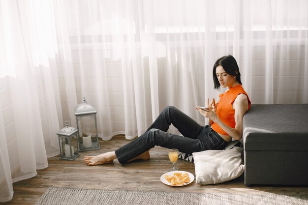 Girl by the window on the floor using a mobile phone.