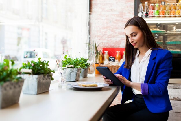 Girl in a cafe reads something on the tablet