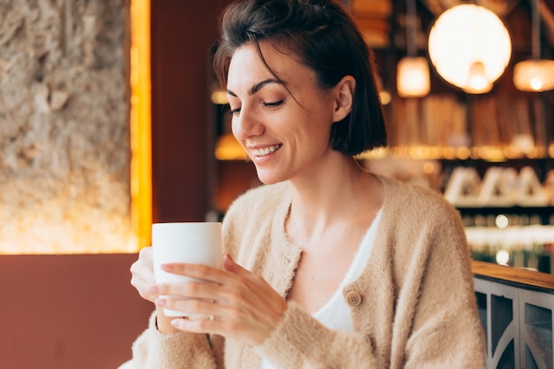 Ragazza in un caffè con una tazza di caffè latte caldo