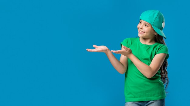 Free photo girl in cap pointing with hands in studio