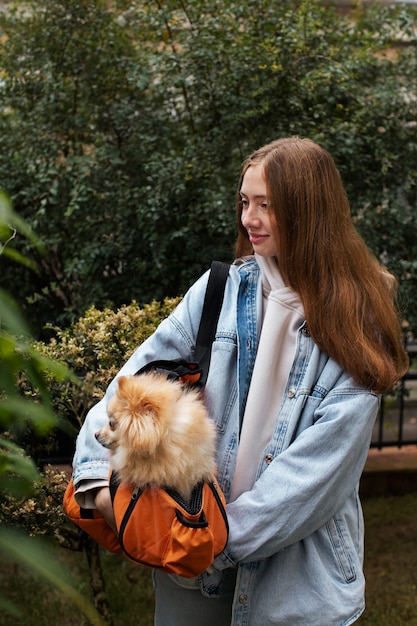 Free photo girl carrying puppy in bag medium shot