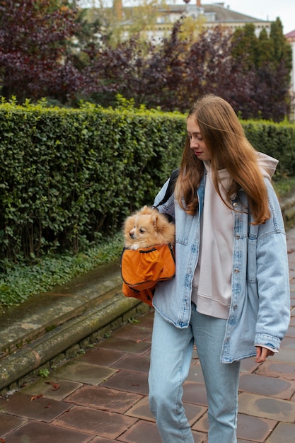 Free photo girl carrying puppy in bag side view