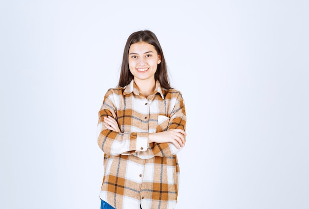  girl in casual clothes standing arms crossed on white wall. 