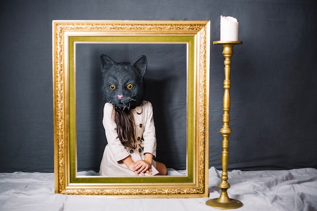 Girl in cat mask behind frame