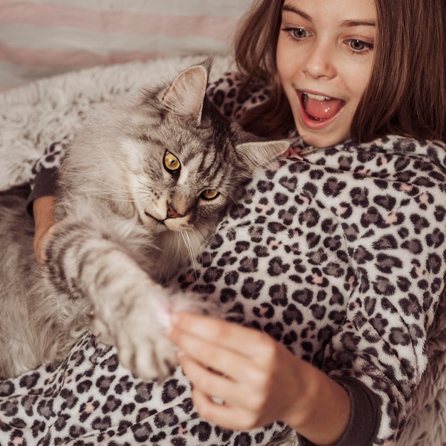 Девушка и кошка играют в постели