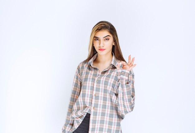 Girl in checked shirt showing ok hand sign