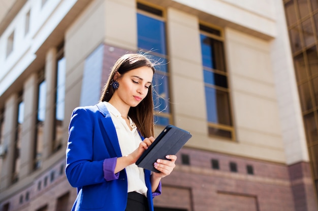 Girl checks her tablet standing on the street