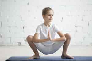 Free photo girl child in malasana pose, white studio background