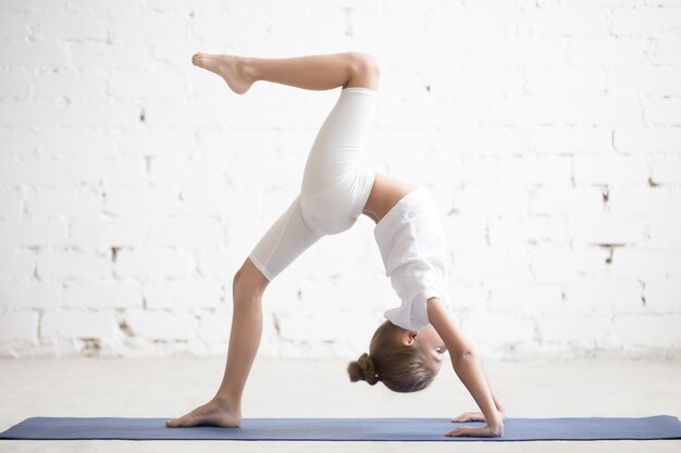 Girl child in One legged Wheel pose, white studio background