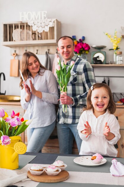 Girl clapping hands near parents with flowers