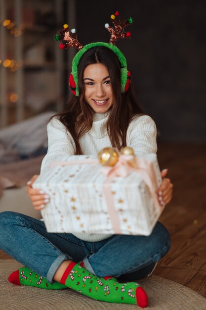 소녀는 카메라에 미소 선물 닫습니다. 그녀는 크리스마스 뿔을 입고있다.