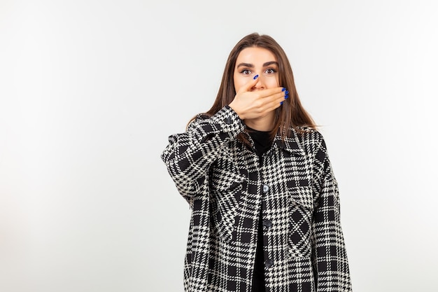 Foto gratuita una ragazza chiuse la bocca con la mano e in piedi su sfondo bianco