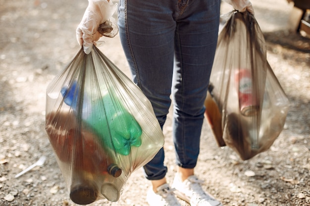 Girl collects garbage in garbage bags in park