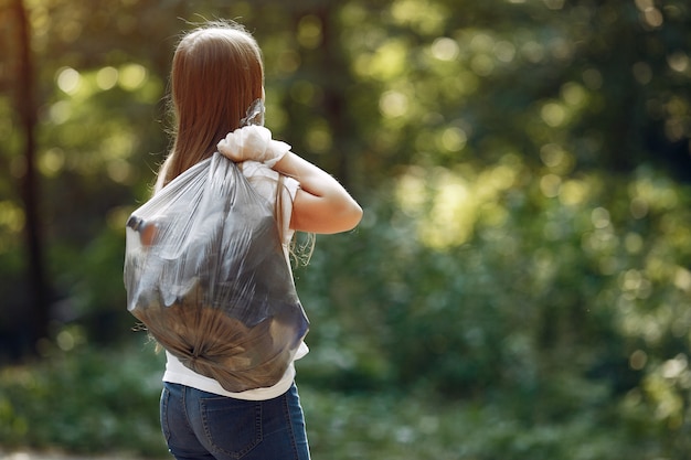 Girl collects garbage in garbage bags in park