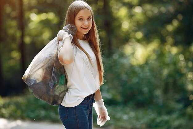 Girl collects garbage in garbage bags in park